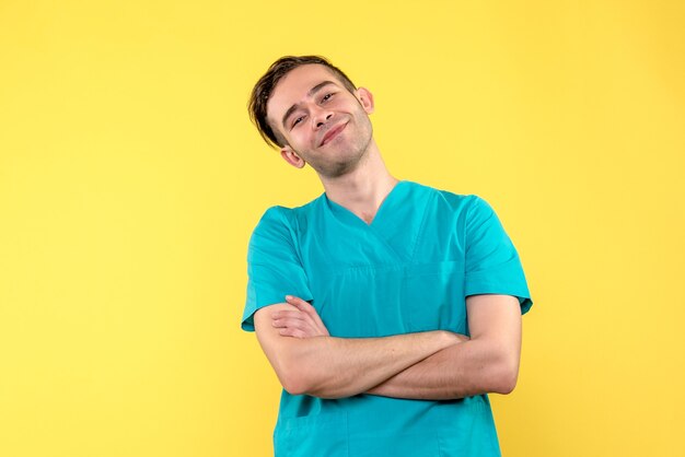 Front view of male doctor smiling on yellow wall