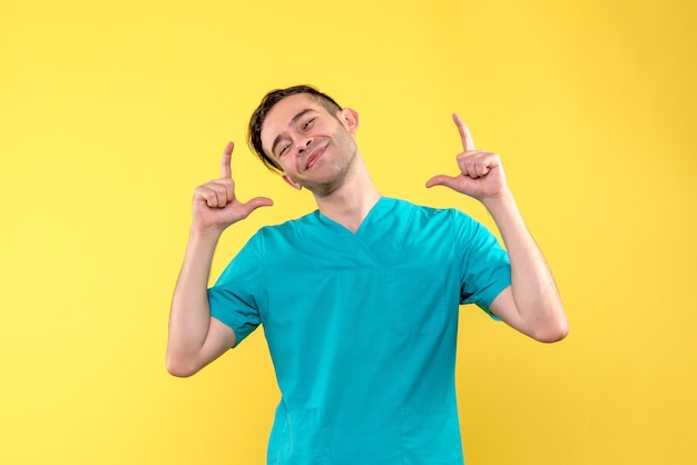 Front view of male doctor smiling on yellow wall