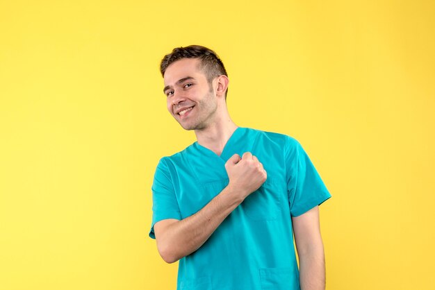 Front view of male doctor smiling on yellow wall