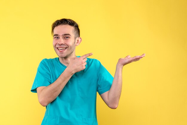 Front view of male doctor smiling on yellow wall