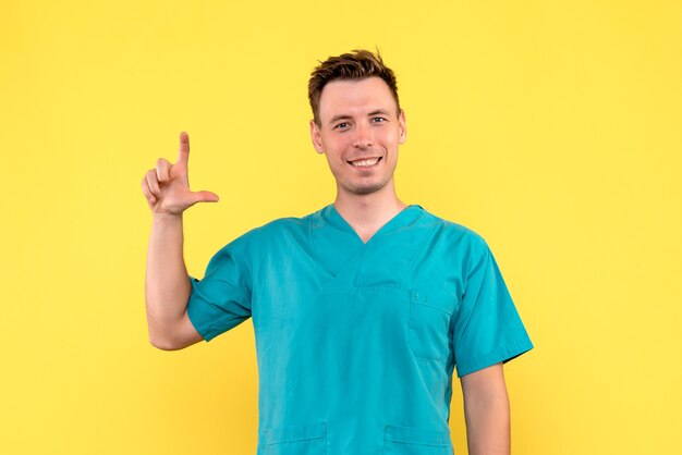 Front view of male doctor smiling on yellow wall