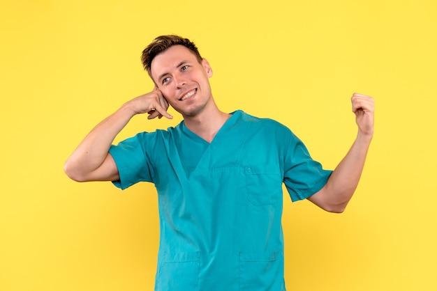 Front view of male doctor smiling on yellow wall