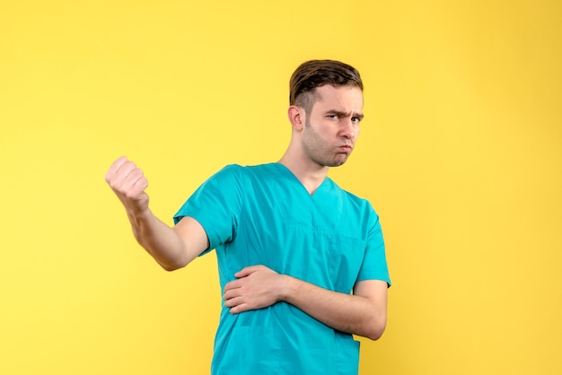 Front view of male doctor smiling on yellow wall