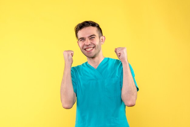 Front view of male doctor so excited on yellow wall