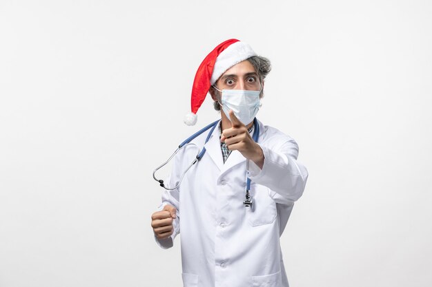 Front view male doctor in sterile mask on a white wall covid virus new year holiday