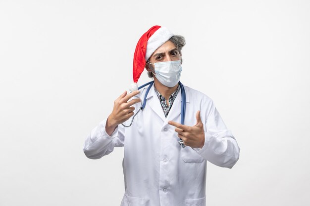 Front view male doctor in sterile mask on white wall covid virus new year holidays