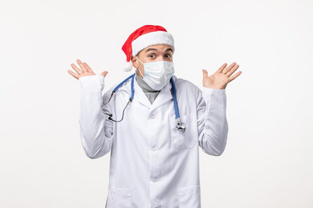 Front view of male doctor in sterile mask on white wall