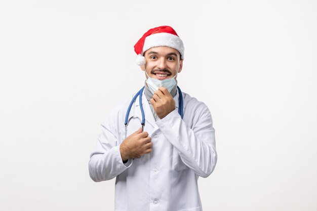 Front view of male doctor in sterile mask on white wall