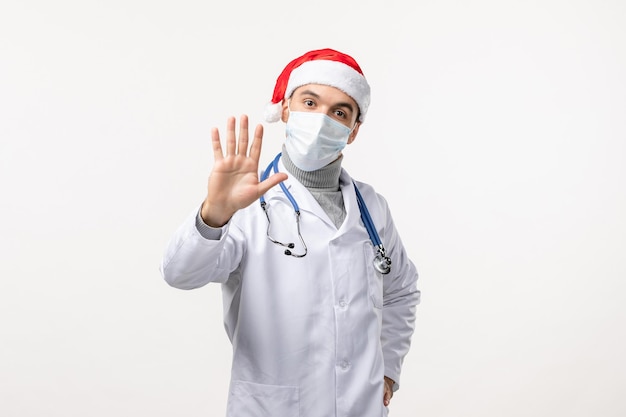 Front view of male doctor in sterile mask on white wall