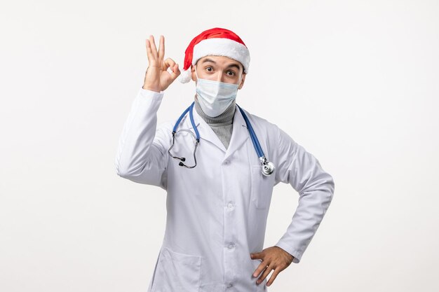 Front view of male doctor in sterile mask on white wall