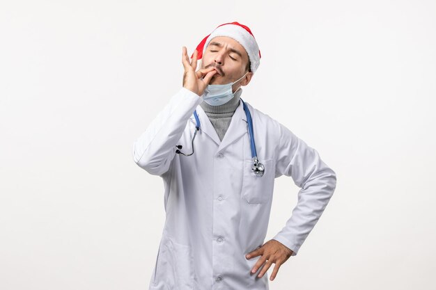 Вид спереди мужского врача в стерильной маске на белой стене