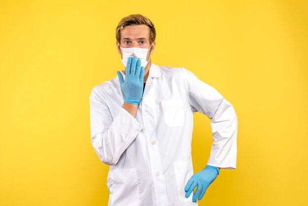 Front view male doctor in sterile mask on yellow background health covid virus pandemic