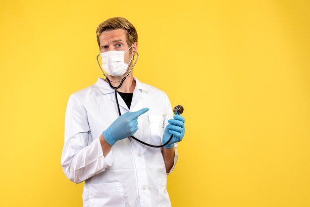 黄色の背景のパンデミックウイルスcovid健康の無菌マスクの正面図男性医師