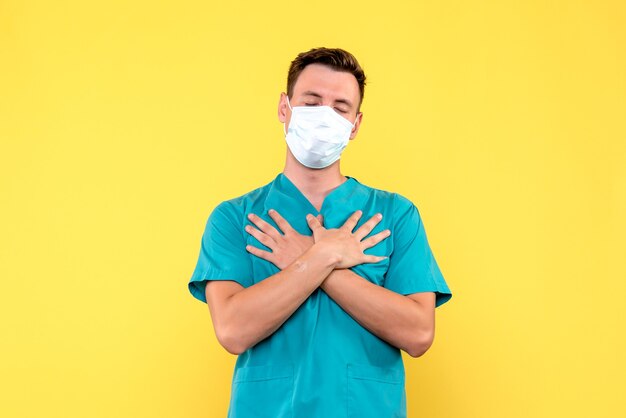 Front view of male doctor in sterile mask on a yellow wall