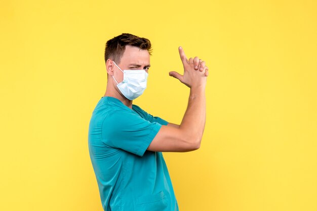 Front view of male doctor in sterile mask on yellow wall