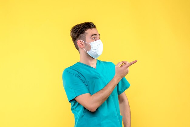 黄色の壁に滅菌マスクで男性医師の正面図