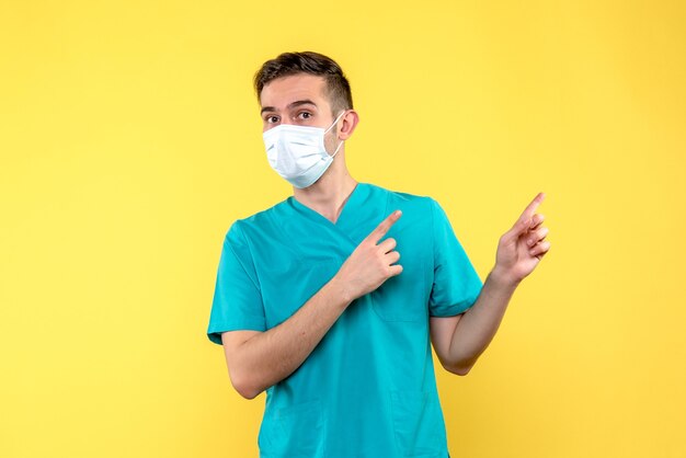 Front view of male doctor in sterile mask on yellow wall