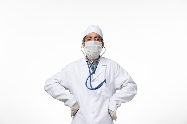 흰색 표면에 코로나 바이러스로 인해 멸균 의료 복과 마스크의 전면보기 남성 의사