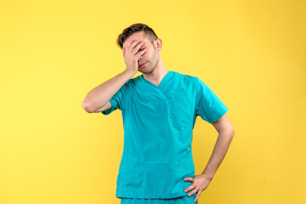 Front view of male doctor stressed on yellow wall