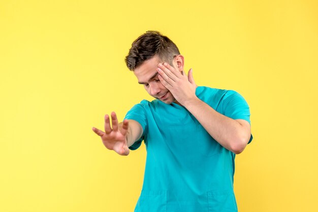 Front view of male doctor stressed on yellow wall