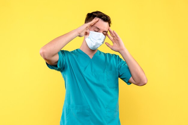 Front view of male doctor suffering from headache on yellow wall