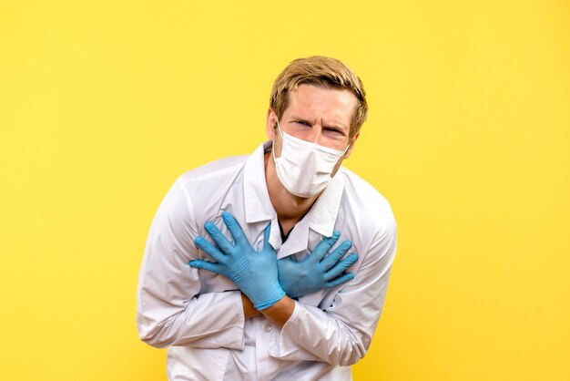 Front view male doctor suffering from pain on yellow background health covid- medic pandemic