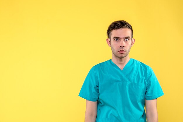 Front view of male doctor surprised on yellow wall