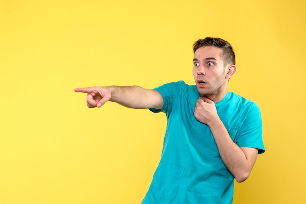 Front view of male doctor surprised on yellow wall