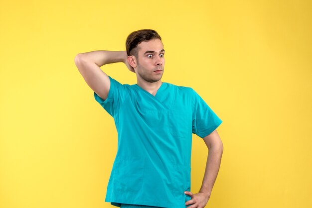 Front view of male doctor surprised on yellow wall