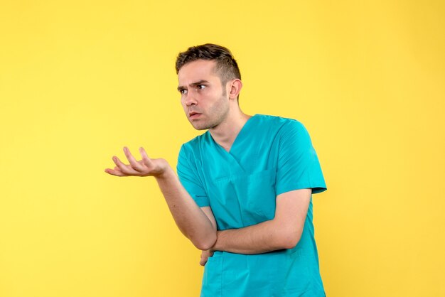 Front view of male doctor talking to someone on yellow wall