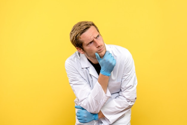 黄色の背景covid-人間の薬の感情を考える正面図男性医師