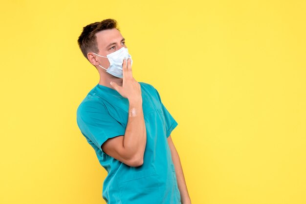 Front view of male doctor thinking on yellow wall