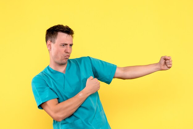 Front view of male doctor trying to dance on yellow wall