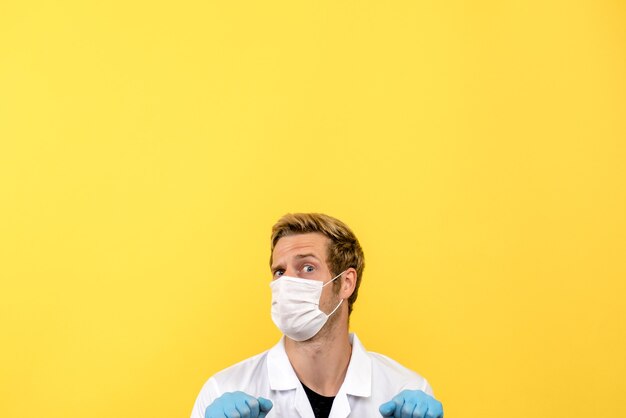 Front view male doctor trying to hide on yellow background covid pandemic health medic