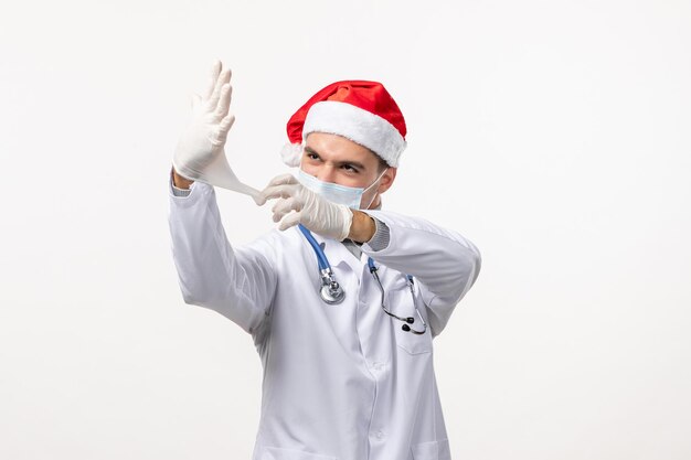 Front view of male doctor wearing gloves on white wall