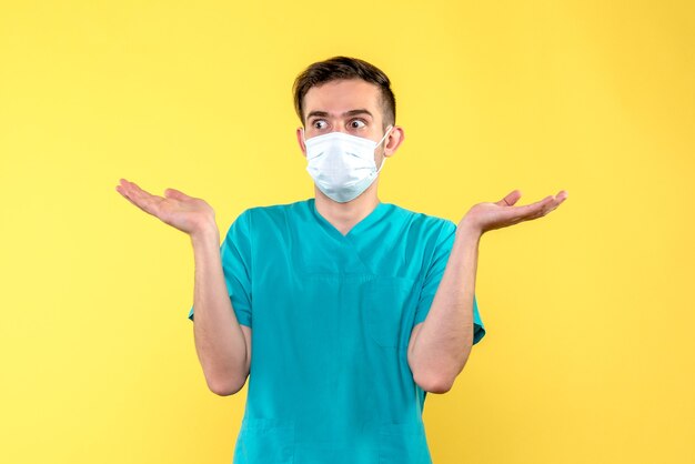 Front view of male doctor wearing mask on yellow wall