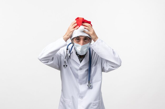 白い壁に赤い帽子をかぶった正面図男性医師新年コビッドウイルスパンデミック