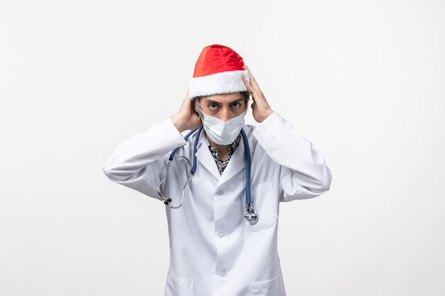 Front view male doctor wearing red cap on white wall virus new year covid pandemic