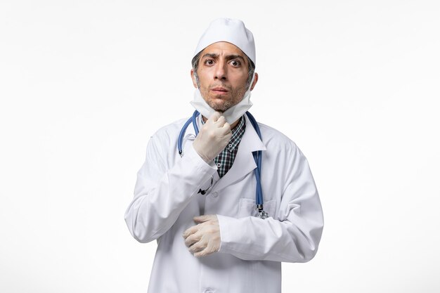 白い表面のコロナウイルスによる白い医療スーツの正面図男性医師