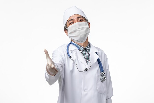 밝은 흰색 표면에 covid로 인해 마스크를 쓰고 흰색 의료 소송에서 전면보기 남성 의사