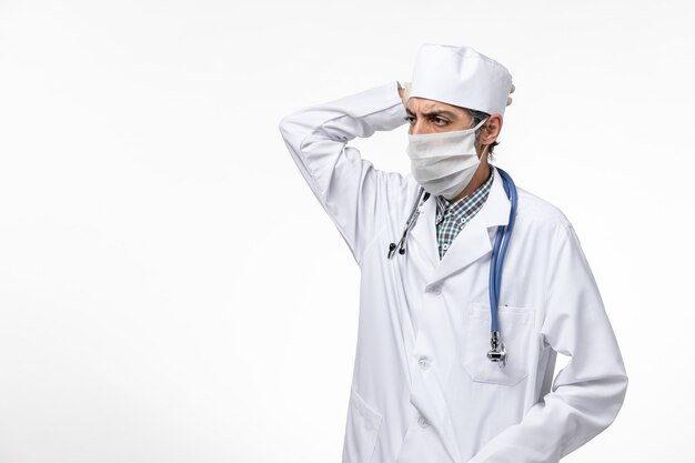 白い表面にコロナウイルス思考のためマスクと白い医療スーツの正面図男性医師