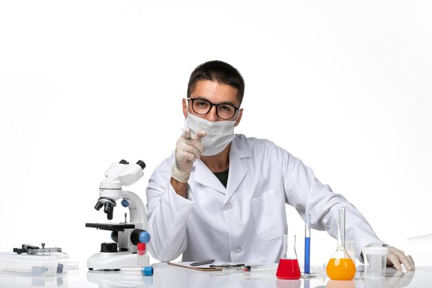 Front view male doctor in white medical suit with mask due to covid on white space