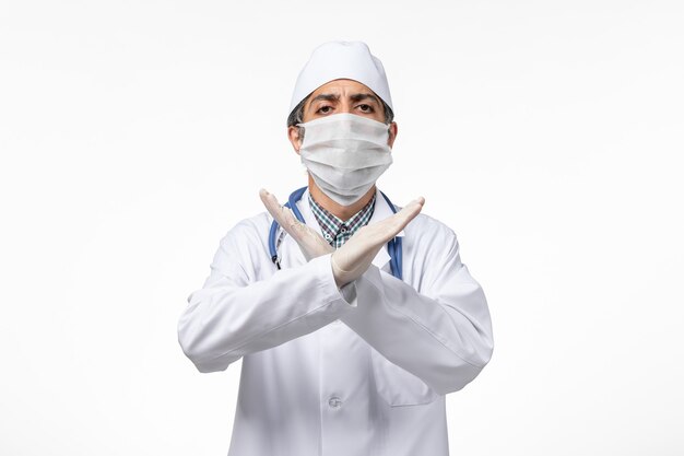 흰색 표면에 covid로 인해 마스크와 흰색 의료 소송에서 전면보기 남성 의사