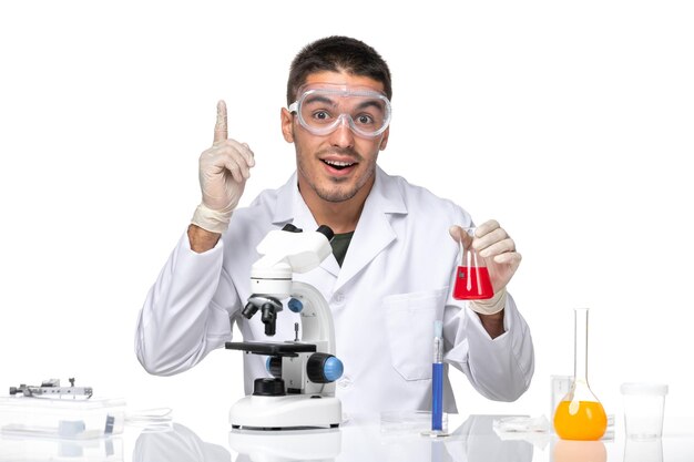 Front view male doctor in white medical suit with protective sunglasses on white space