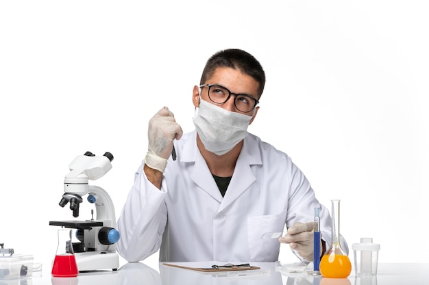 Вид спереди мужчина-врач в белом медицинском костюме, работающий и пишущий на белом пространстве