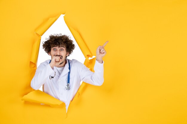 Front view male doctor in white medical suit on yellow ripped medicine color medic health virus
