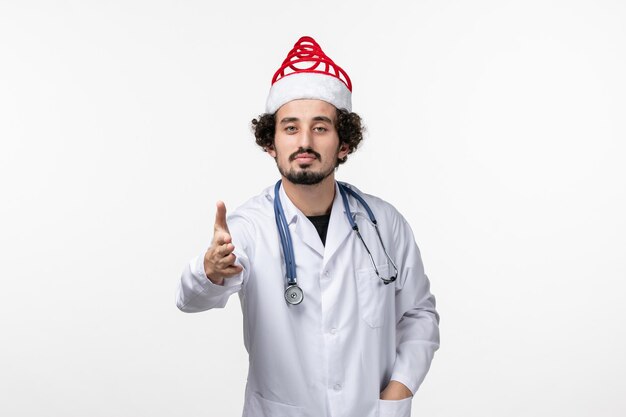 Front view of male doctor on a white wall