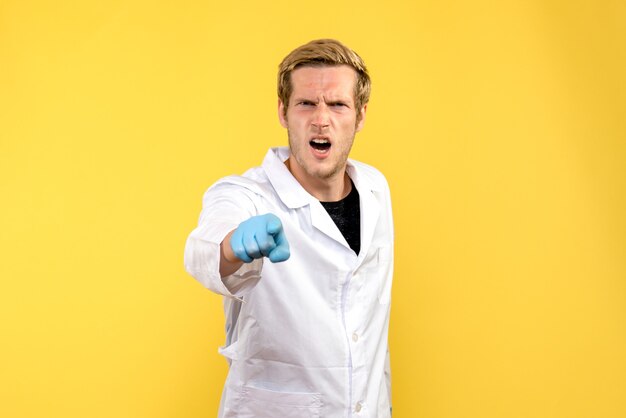 Front view male doctor with angry face on yellow background medic pandemic covid human