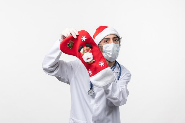 흰색 책상에 큰 휴일 양말과 전면보기 남성 의사 covid 크리스마스 바이러스