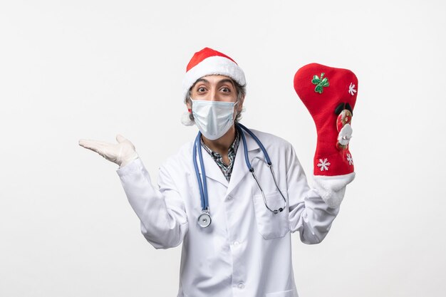 白い床のcovidクリスマスウイルスに大きな休日の靴下を持つ正面図の男性医師